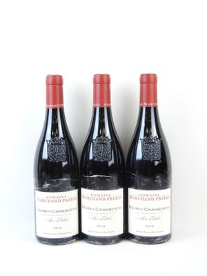 trois bouteilles de vin rouge sont alignées sur une surface blanche