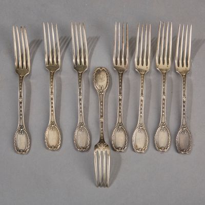 six silverware forks and spoons are lined up on a gray surface