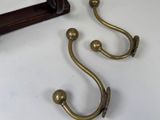 two brass hooks on the wall next to a mirror