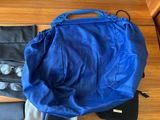 a blue bag and a pair of sunglasses on a wooden floor
