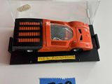 une petite voiture miniature dans une boîte transparente posée sur une table