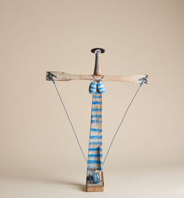 une sculpture représentant une croix, réalisée en bois et en fil de fer