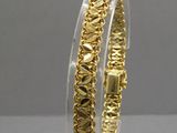 un gros plan d'un bracelet plaqué or posé sur un socle transparent