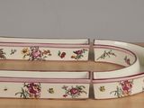 a white bowl with pink and yellow flowers on it on a table