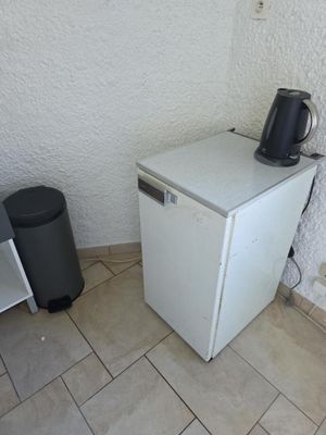un petit réfrigérateur blanc dans le coin d'une pièce