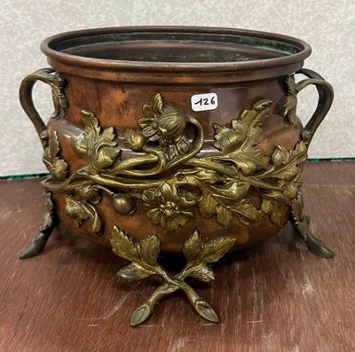 un grand pot en métal orné de fleurs, posé sur une table en bois