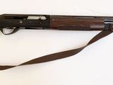 le fusil est posé sur une surface blanche, avec une sangle marron