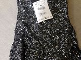 a black and silver sequinned dress with a tag on it