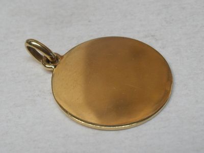 an image of a gold plated pendant on a white surface