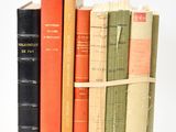 several old books are stacked on top of each other on a white surface