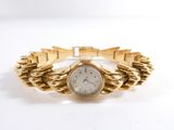 an image of a woman ' s wrist watch on a gold bracelet
