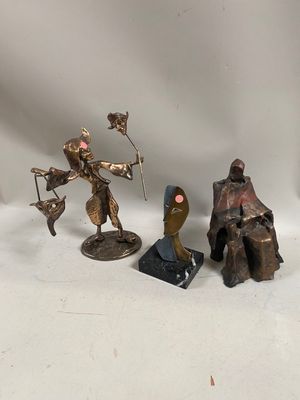 three bronze figurines of a man and a woman sitting on a bench