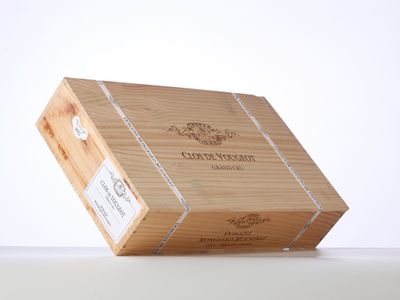 une boîte en bois ouverte, sur laquelle est collée une étiquette, posée sur une table