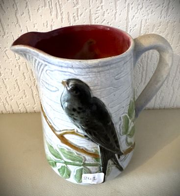 un pichet en céramique orné d'un oiseau, posé sur une table