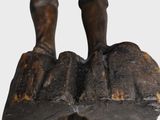 statue of a man standing on top of a rock with his hands in his pockets