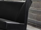 a black couch that is on wheels in front of a brick wall