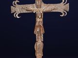 une vieille croix en métal posée sur un socle, sur fond bleu