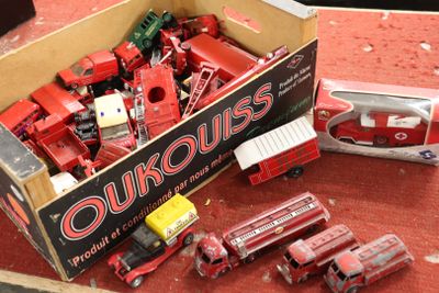 une boîte remplie de camions rouges en plastique posée sur un tapis rouge