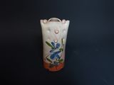 a white vase with blue flowers on it on a black surface