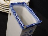a blue and white vase sitting on a table next to a stack of plates