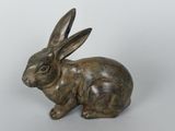 sculpture en bronze représentant un lapin assis sur une surface blanche