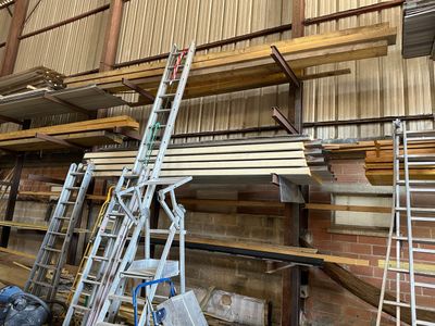 several ladders are sitting in front of a wall of wood planks