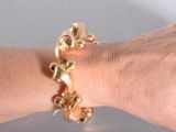 la main d'une femme à laquelle est attaché un bracelet en or