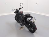 a black motorcycle parked in a room with a white wall