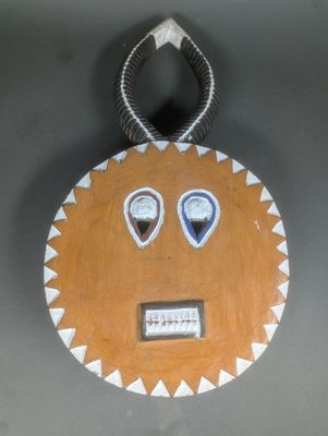 une photo d'un masque en bois accroché à un mur