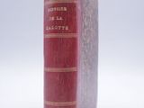 an old red book sitting on top of a white surface