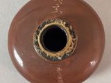 a brown vase with a black hole in it