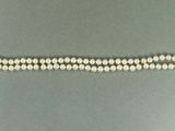un gros plan d'un bracelet en perles blanches posé sur une surface grise