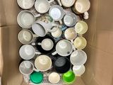 a cardboard box filled with cups and saucers