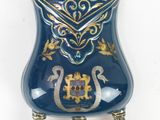 a blue vase with a gold decoration on it