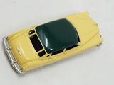 a yellow toy car with a green top on a white surface