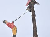 a figurine of a man holding a bird on a pole