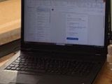 a laptop computer sitting on a desk next to a cell phone