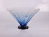 un bol en verre bleu avec un socle noir posé sur une surface blanche