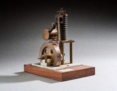 une vieille maquette de machine à vapeur posée sur un socle en bois