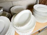 a lot of white plates and bowls on a shelf