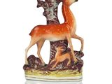 a figurine of a deer and a deer on a tree stump