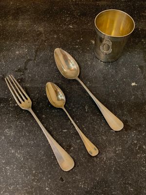 quatre cuillères en argent et une tasse en argent posées sur une table