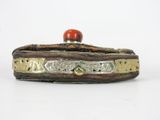 an old silver and gold box with a red stone on top