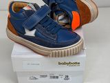des chaussures de bébé bleues à semelles orange, posées sur une boîte blanche