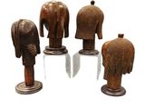 four wooden elephant heads on stands on a white surface