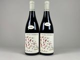two bottles of red wine sitting next to each other on a table