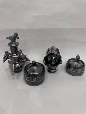 trois figurines en céramique noire sont posées sur une surface blanche