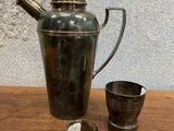 un pichet en métal et une tasse posés sur une table en bois