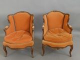 pair of orange velveted chairs with carved wood legs
