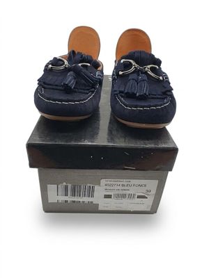 des chaussures en cuir bleu marine ornées de pompons sur le dessus d'une boîte